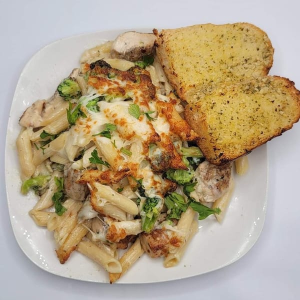Timo's Pizza creamy penne pasta with chicken, broccoli, melted cheese, and two slices of garlic bread.