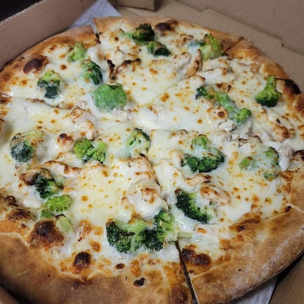 Timo's Pizza chicken and broccoli pizza, with melted white cheese and a golden crust, in a delivery box.